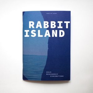Softcover book largely blue in color with large bold white text that reads Rabbit Island at the top, with smaller text at the lower right bottom that reads 2015 Residency Exhibition.